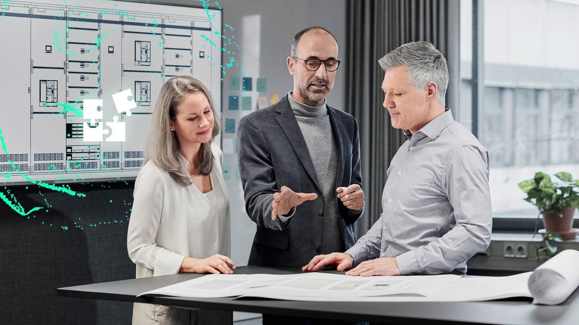 Three people talking at a standing desk; a stylized digital 3WA air circuit breaker hovers on a project plan in front of them