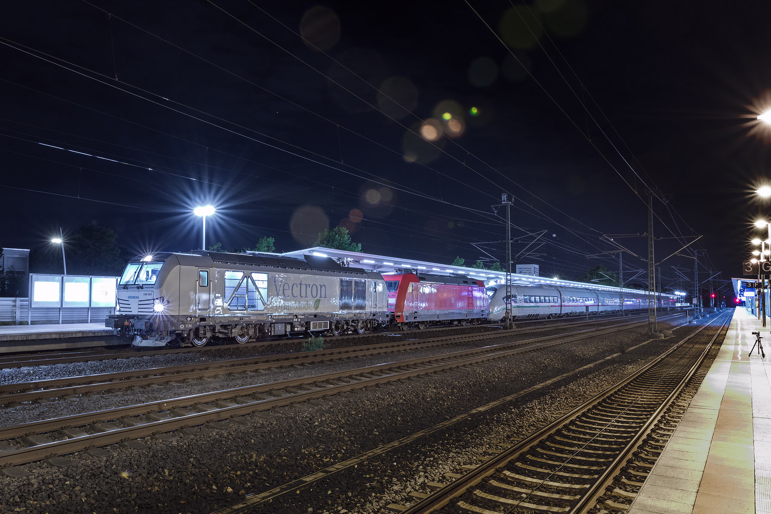Bild eines Vectron Dual Mode am Bahnhof bei Nacht mit einem angehängten ICE Hochgeschwindigkeitszug. Siemens Mobility Lokomotive Vectron Dual Mode mit ICE