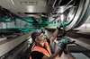 Servicetechniker von Siemens Mobility Rail Services bei der Arbeit unter einem Schienenfahrzeug – überprüft das Laufrad