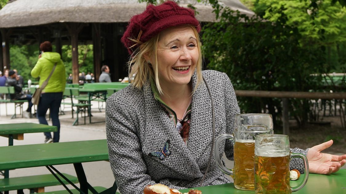  rebecca johnson, especialista em inteligência artificial, sorrindo em frente a duas canecas de cerveja durante entrevista no centro de Munique