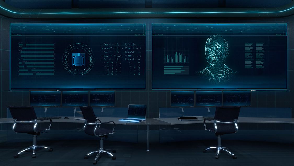 We’re looking at a seemingly state-of-the-art control room. The entire room is bathed in dark blue. At the center of the image, three empty office chairs are placed in front of two large-format, wall-mounted displays showing screen contents from SIMATIC PCS neo.