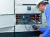 Electrician inspecting circuit breaker panel with handheld device