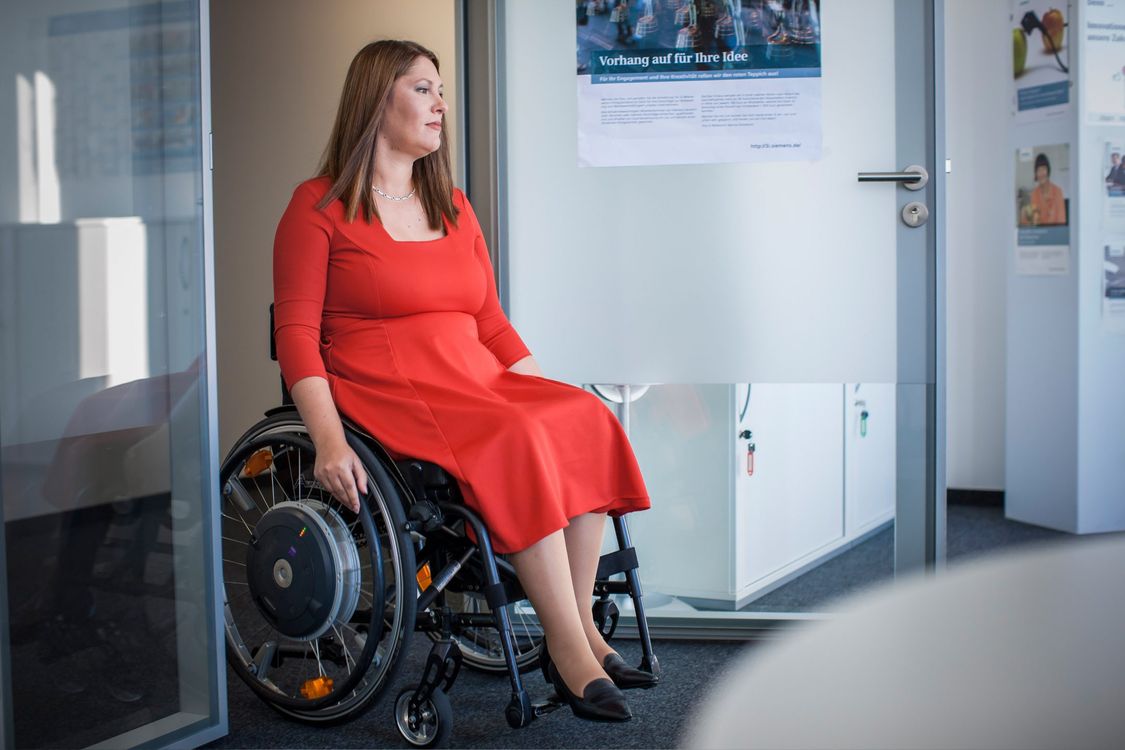 Marina bewegt sich mit ihrem Rollstuhl in den Büroräumen