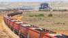 kilometerlanger Güterzug mit Fracht fährt durch eine Wüste