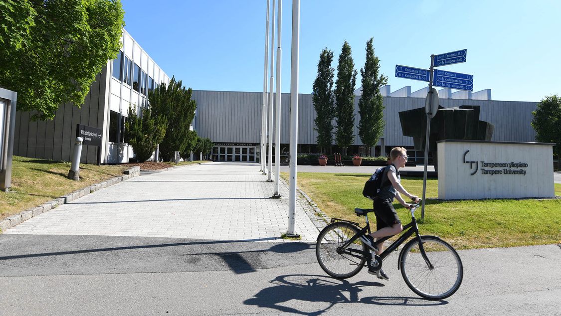 Ein Student verlässt mit seinem Fahrrad den Campus der Tampere University.