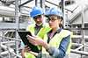 A woman and a man look at a tablet in a chemical plant