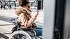 Eine Passagierin im Rollstuhl genießt ein verbessertes Reiseerlebnis dank intermodaler Reise-Apps, die ihr genau sagen, wohin sie gehen muss, während sie multimodale Mobilitätssysteme bedient