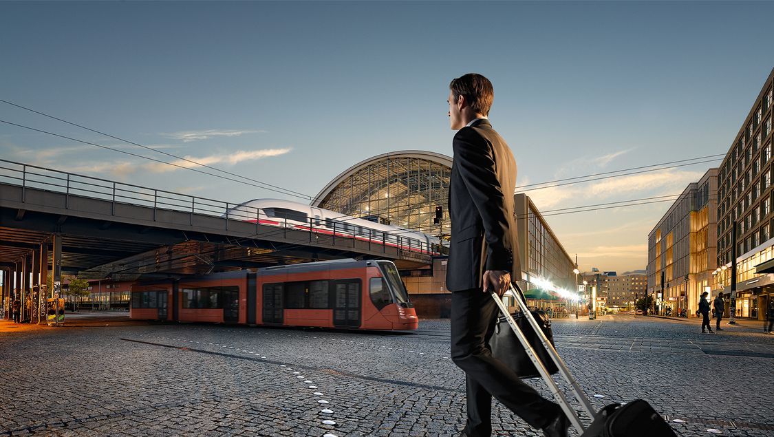 Man carrying a suitcase in front of a Siemens train