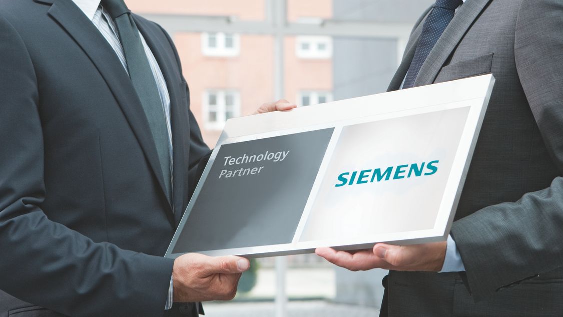 Two business partners handing over the Siemens technology partner badge.