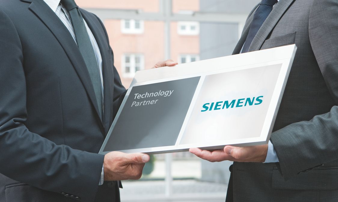 dois homens de terno seguram ao mesmo tempo uma placa do Technology Partner o programa de parceria de paineis elétricos da siemens