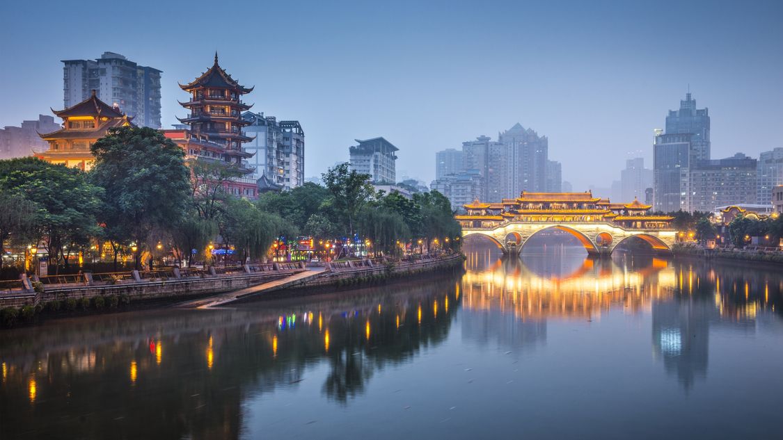  Imagem de rio que corta a cidade chinesa chengdu com ponte iluminada e ao fundo os grandes prédios da cidade