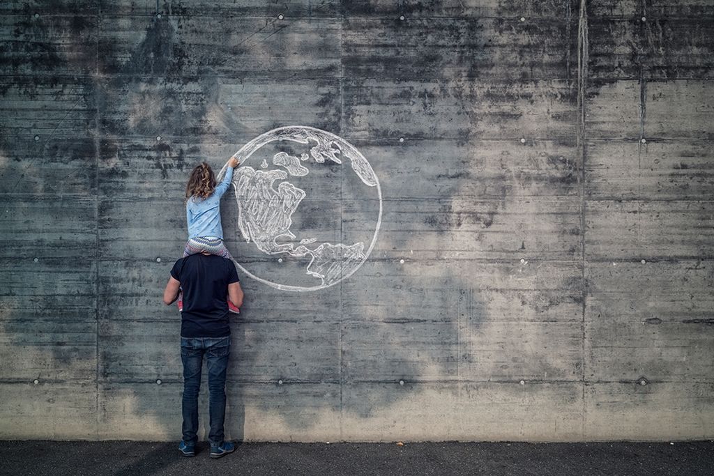 father-with-daughter-on-his-shoulders-the-daughter-drawing-the-earth-onto-a-concrete-wall-with-chalk-large.jpeg