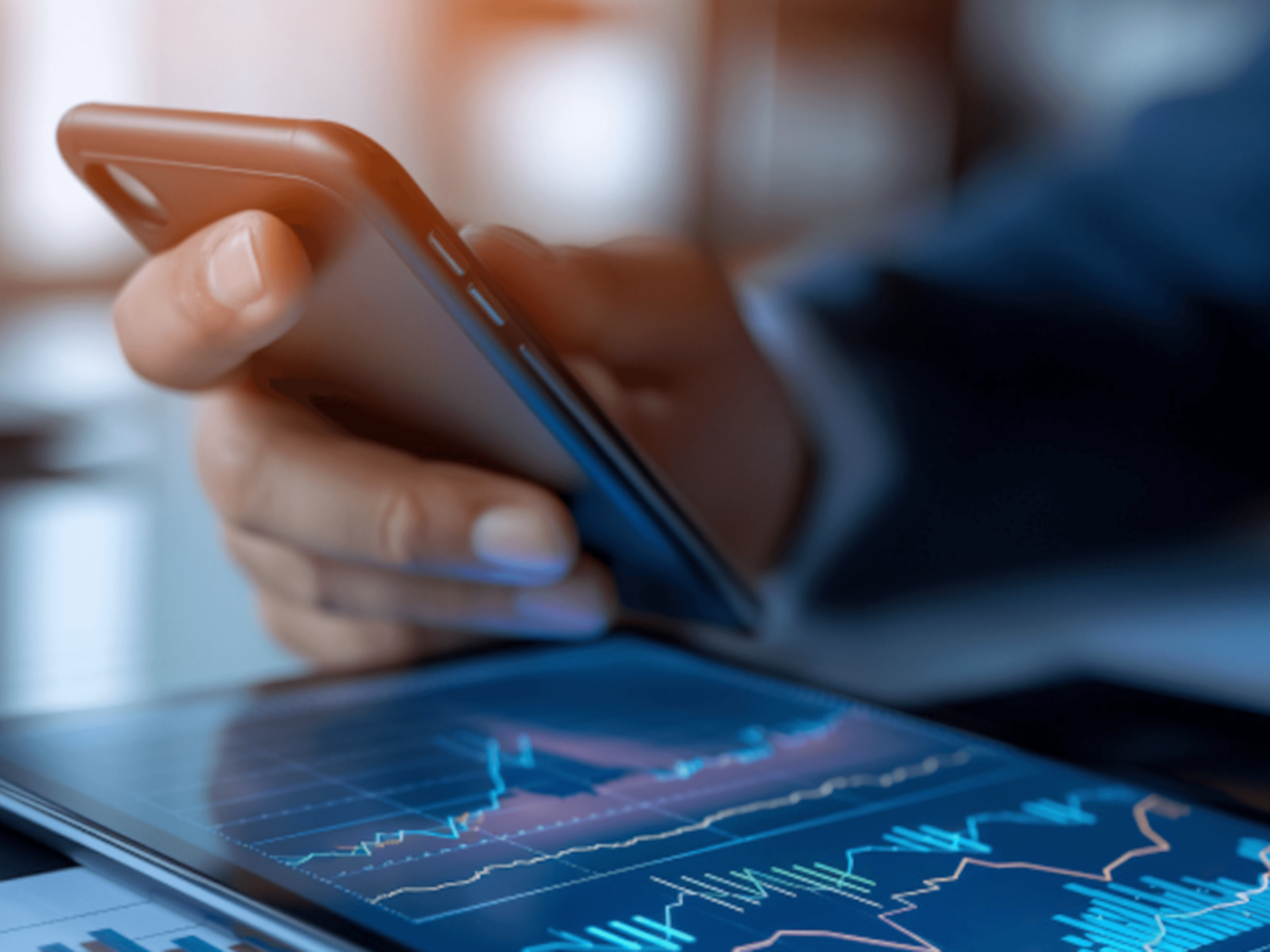 Håndeholder telefonen over finansielle diagrammer