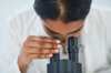 Female scientist looks through microscope