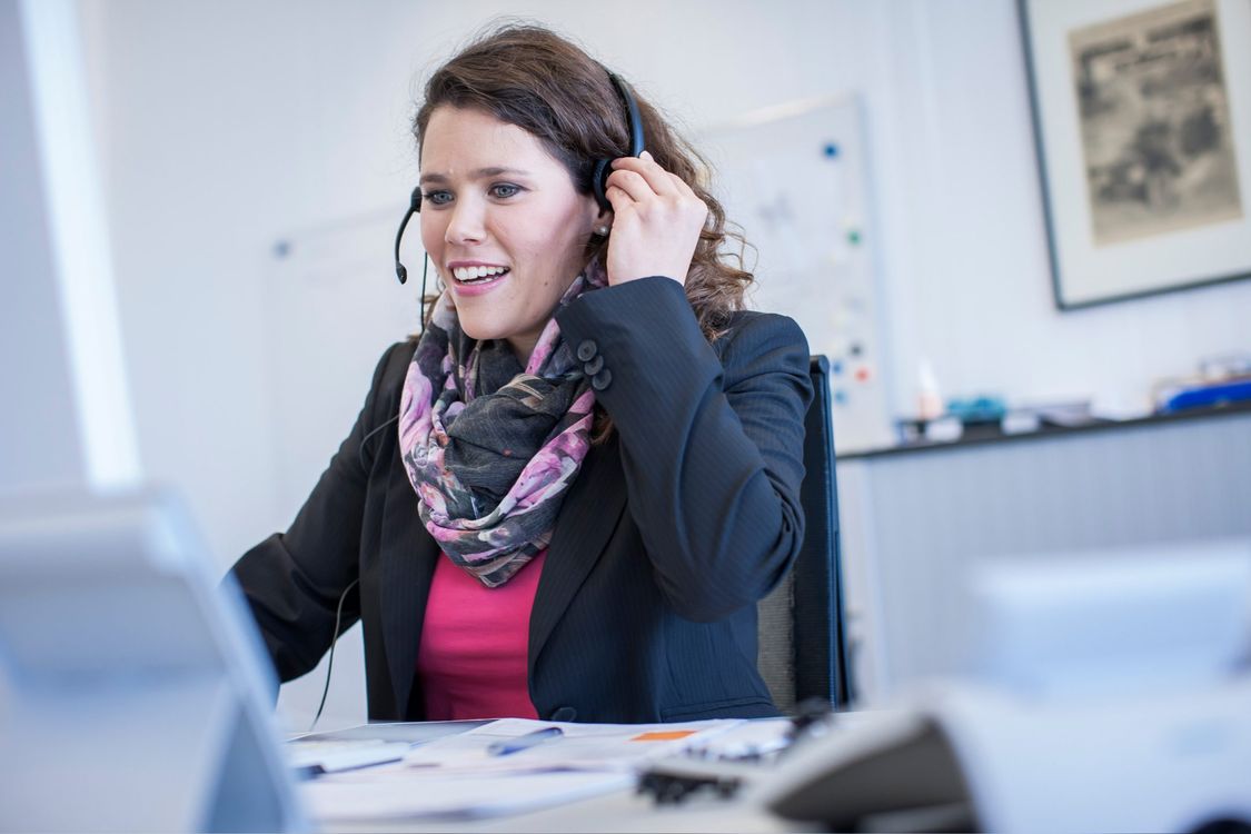 Christina sitzt mit einem Headset am Schreibtisch