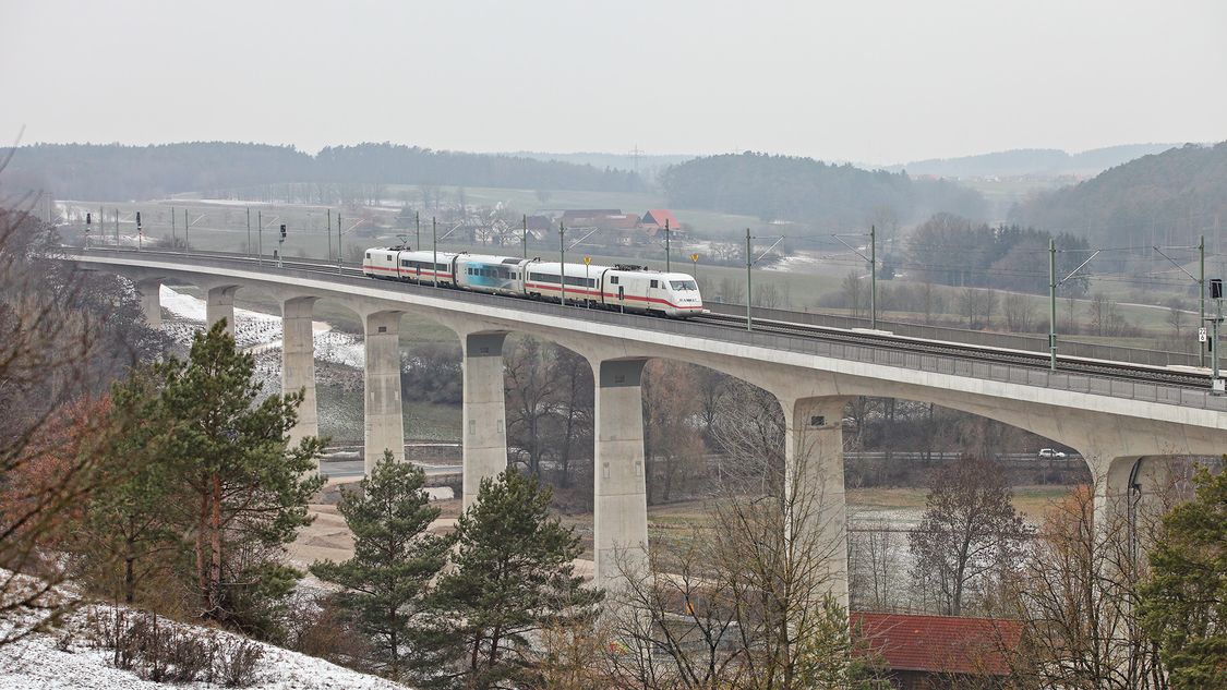 Test car of the Velaro Novo in use coupled between existing train cars on a bridge surrounded by wintry landscape