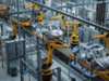 An automated automotive manufacturing assembly line featuring multiple yellow industrial robotic arms arranged in sequence. An automated automotive manufacturing assembly line featuring multiple yellow industrial robotic arms arranged in sequence.
